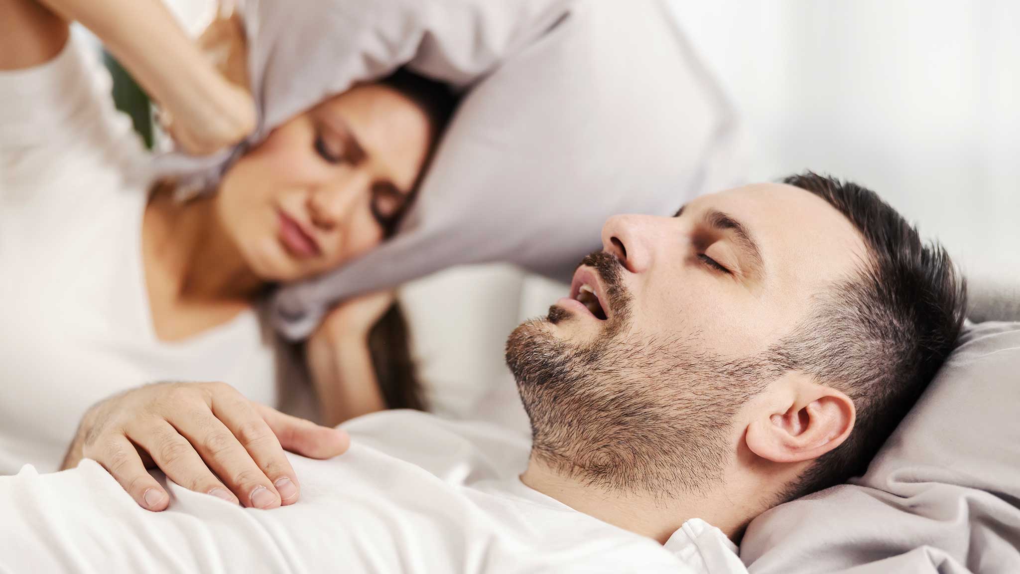 Uomo che russa e donna che si copre le orecchie