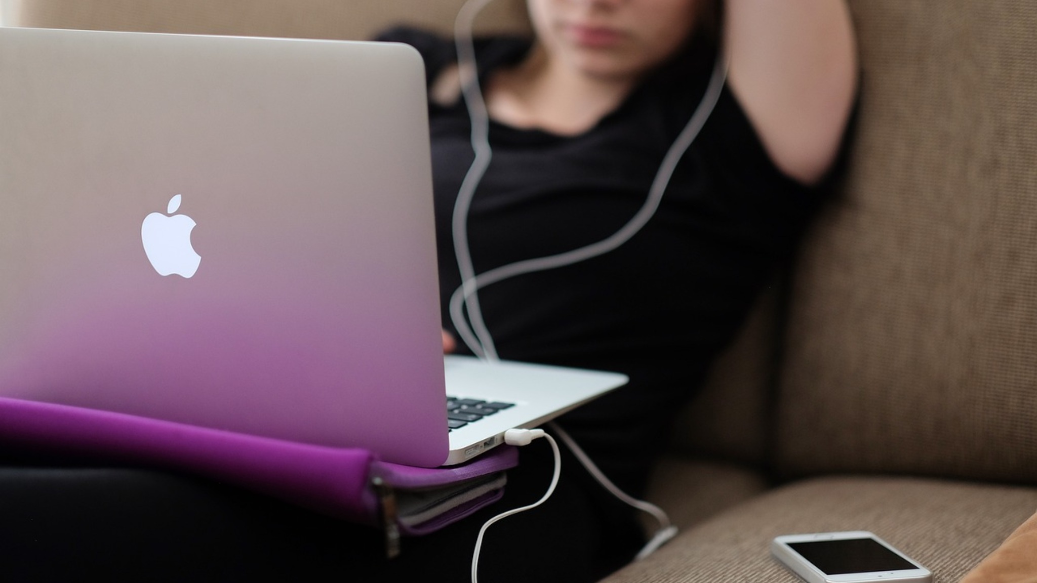donna sul divano con macbook in primo piano